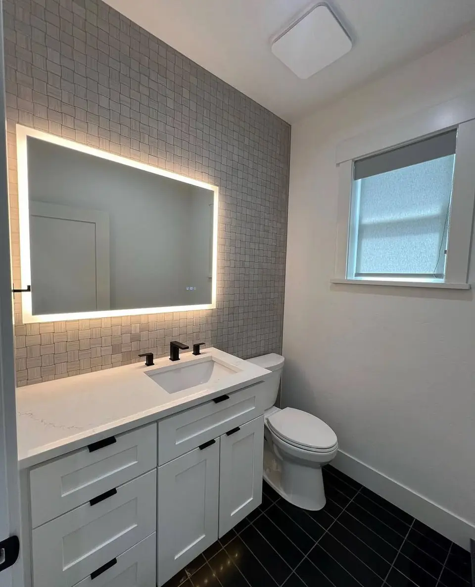 Bathroom remodel with backlit LED mirror, mosaic tile accent wall, white shaker vanity with matte black fixtures and dark tile floor