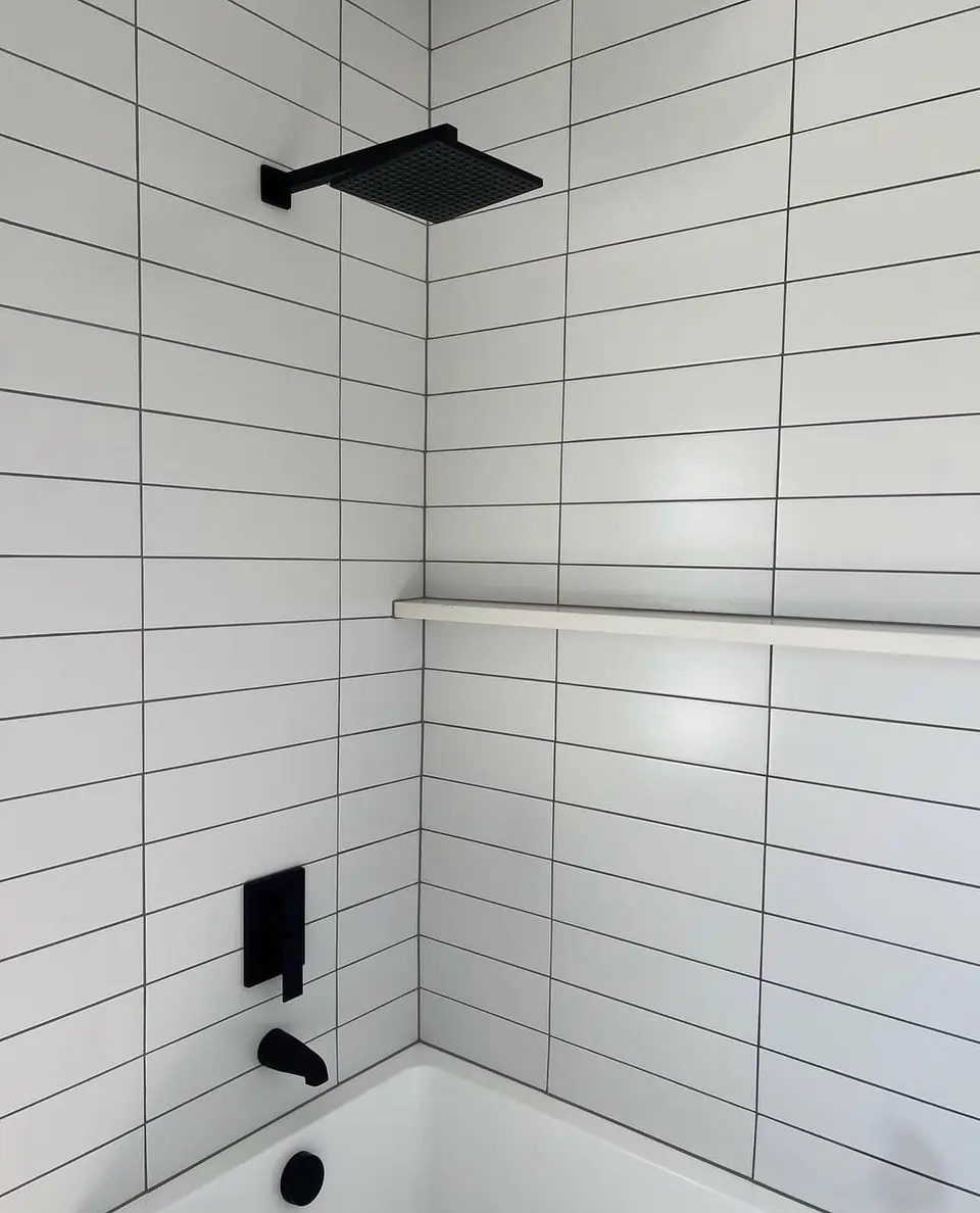Shower and tub surround in white subway tile with a matte black rain shower head and fixtures